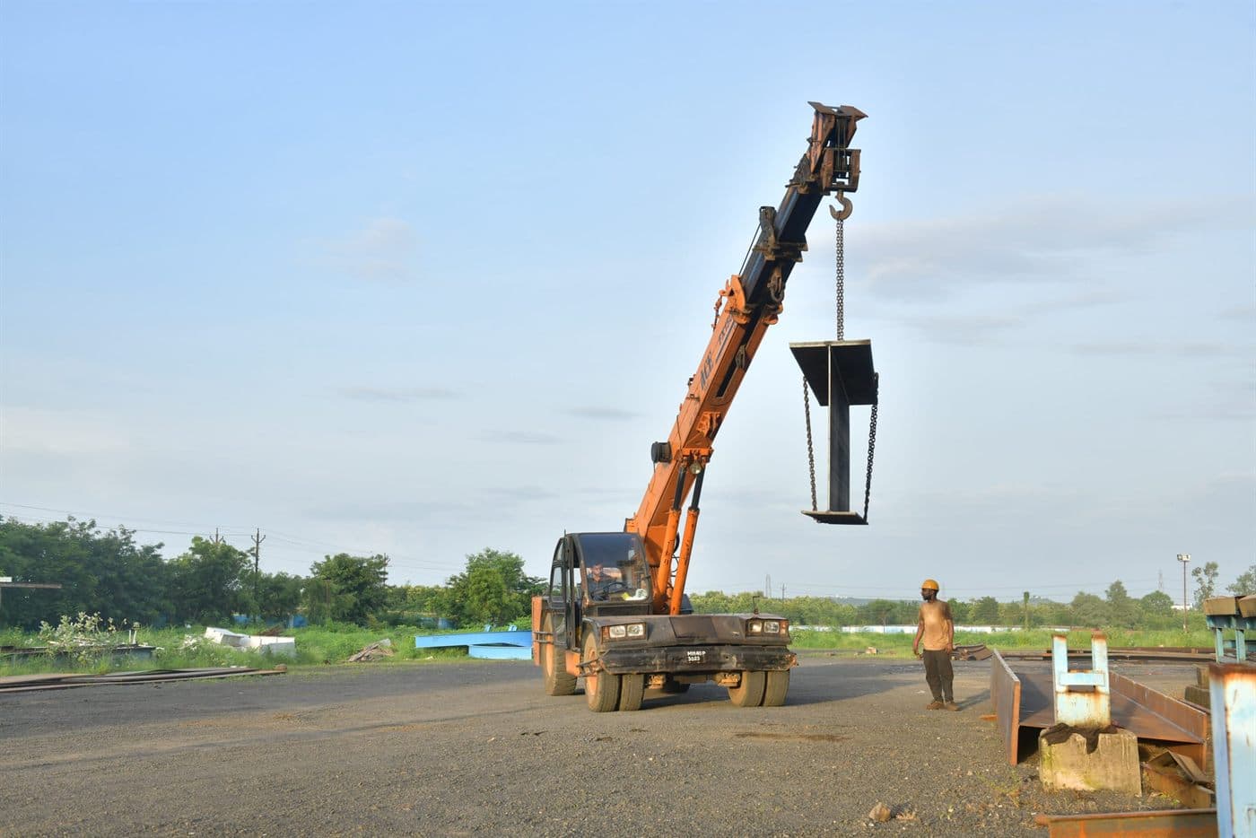 Mobile crane lifting a fabricated beam in the yard